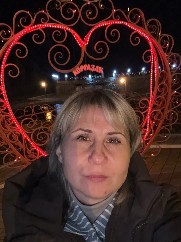 Woman stands by illuminated heart structure in Komsomol nighttime display