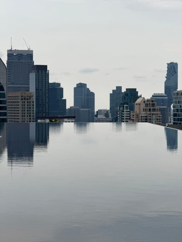 Bangkok skyline reflections captured in water during hazy morning