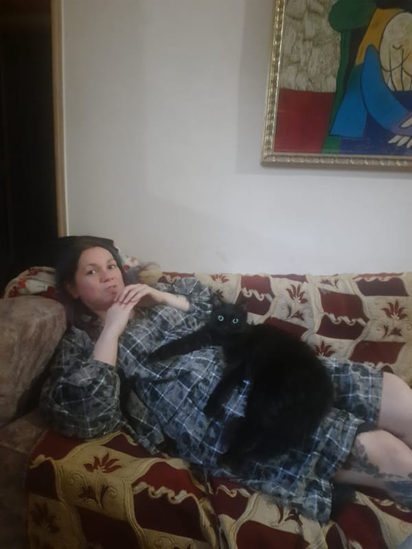 Woman relaxes with black cat on sofa in Al Hadaba