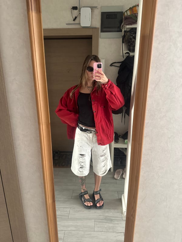 Mirror selfie in Moscow apartment, red jacket and ripped shorts