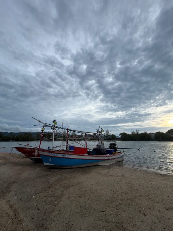 Fishing boats and banana plants along a cloudy Ko Samui shore