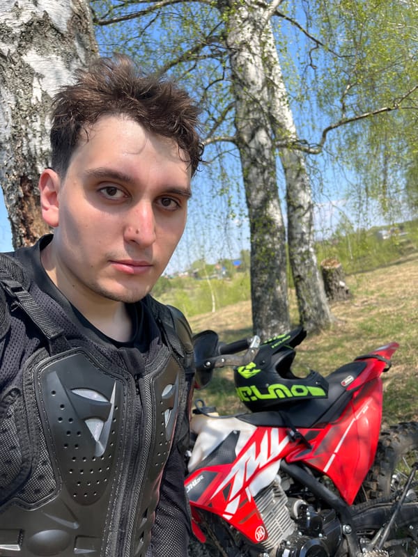 Motorcyclist poses with bike in Russian countryside spring scene