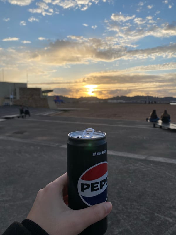 Person enjoys Pepsi during sunset at Gijón beach