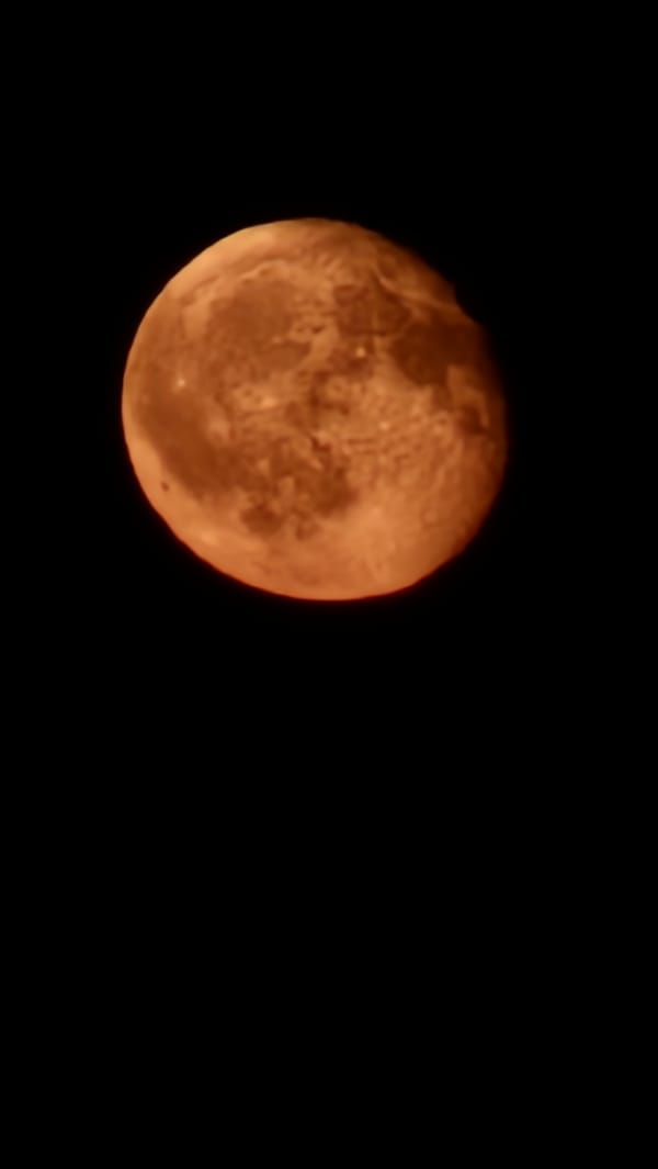 Orange full moon rising over Krasnodar, craters clearly visible