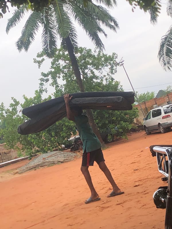 Person carries large object through Nteje, Nigeria