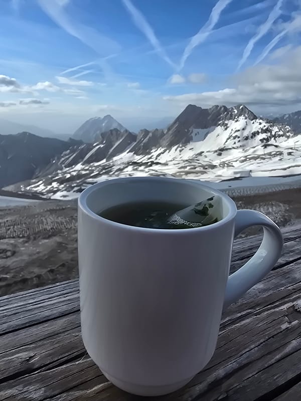 Hot drink on a wooden railing, Alpine peaks behind