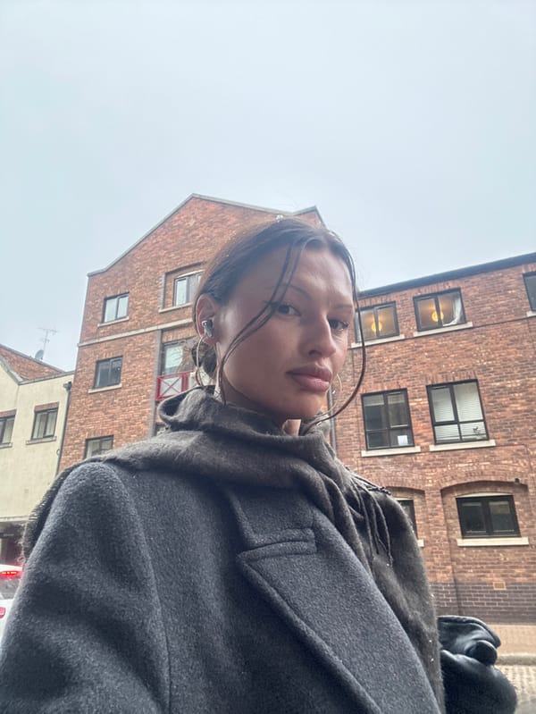 Woman observed in London snowfall wearing earbuds near vehicle