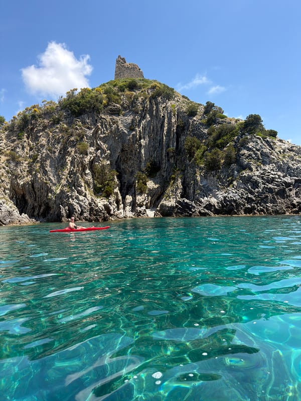 Kayaker paddles near Ascea cliffs in turquoise Mediterranean waters