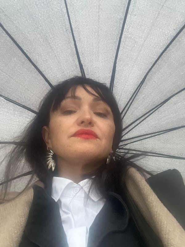 Woman shelters under umbrella during rainy afternoon in Perm