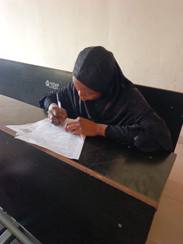 Students writing at desks in Akwanga education college classroom