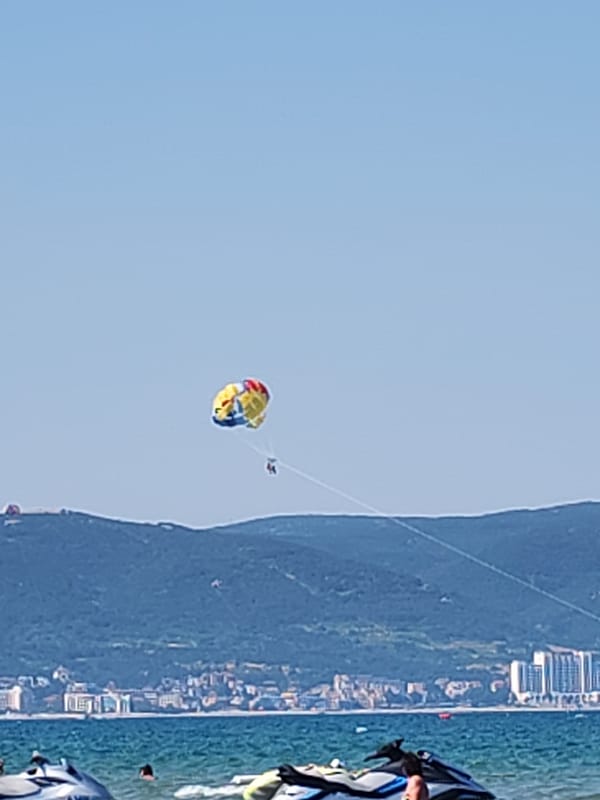 Crowded beach day in Nesebar with parasailing overhead