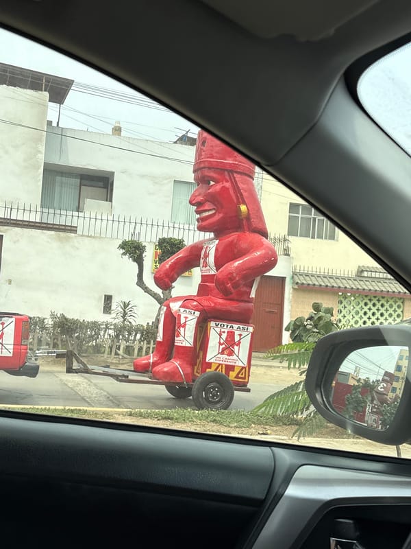 Political parade features red cartoon figure in La Perla Peru