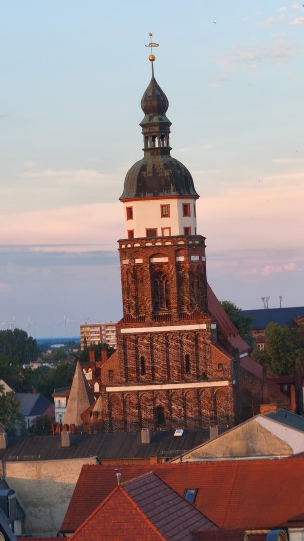 European street festival at dusk with rides, food stalls, and crowds