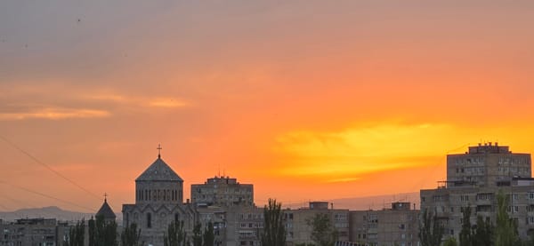 Sunset illuminates Yerevan skyline with church and Soviet buildings