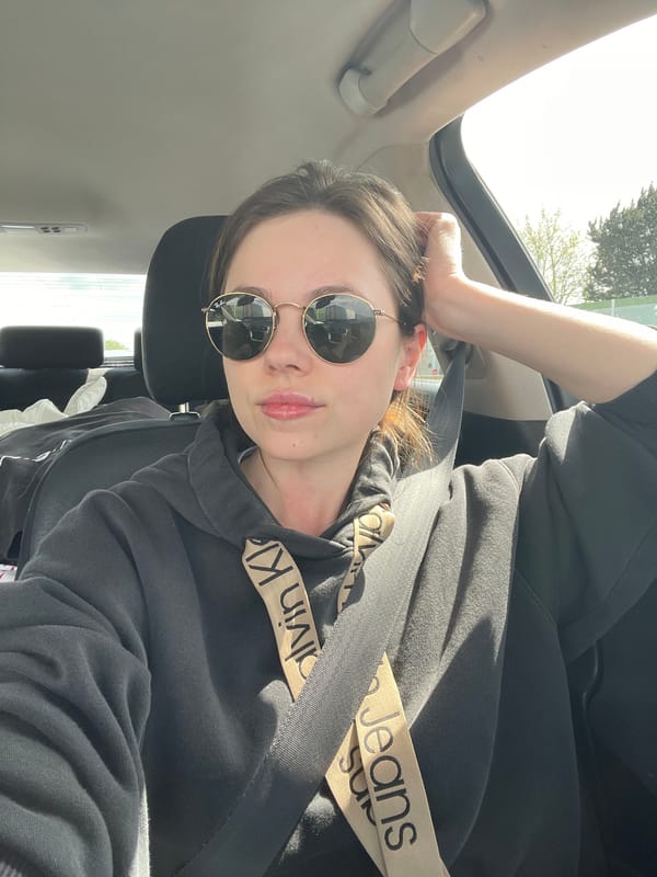 Woman in sunglasses photographed in car with open sunroof