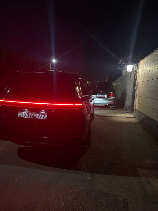 Vehicles parked under carport, SUV tail lights on