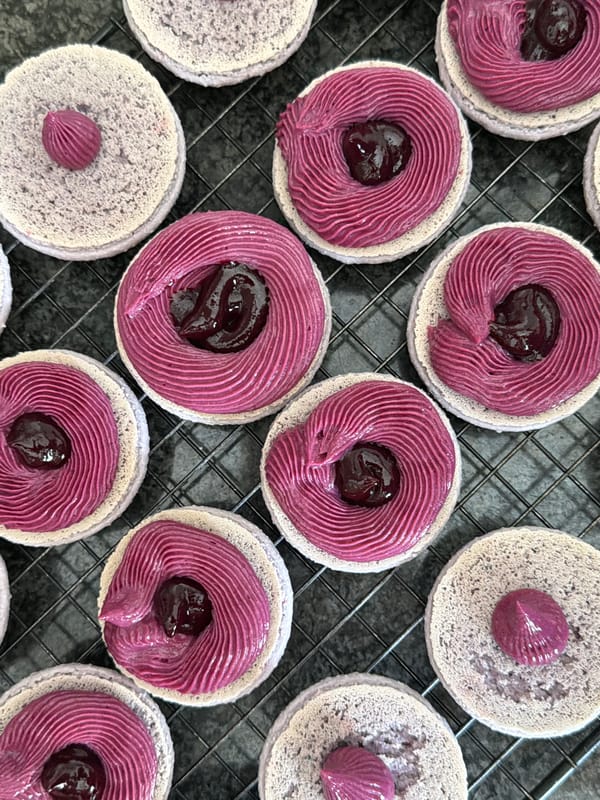 Baker decorates lavender macarons with purple frosting in Tel Aviv
