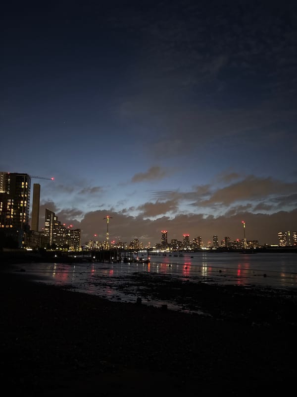 London waterfront captured at night with lit buildings, cranes