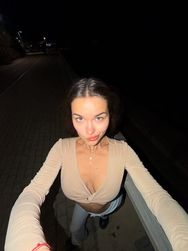 Woman poses for nighttime photos on waterfront promenade
