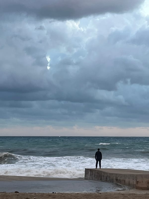 Person stands alone on pier watching turbulent sea in Alanya