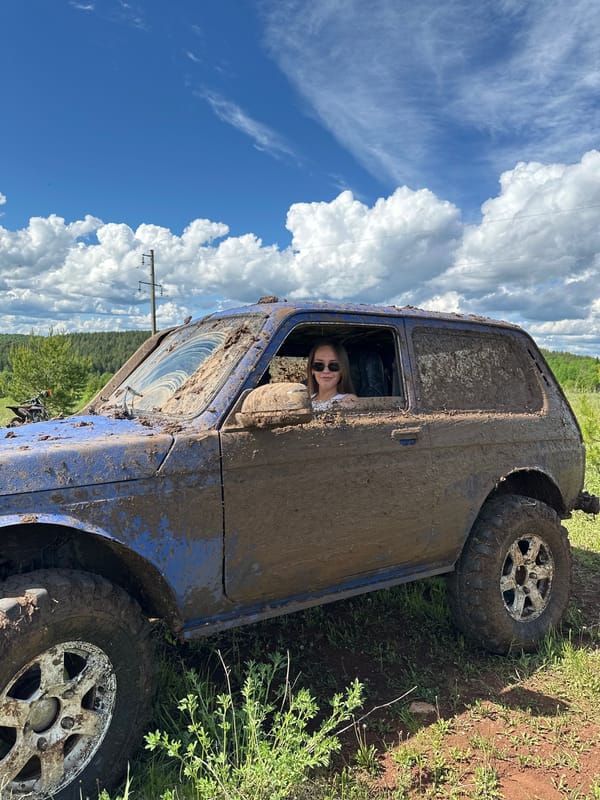 Off-road enthusiasts gather with muddy vehicles in Russian countryside
