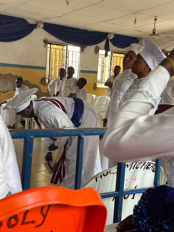 Religious service in community hall with white-robed congregation