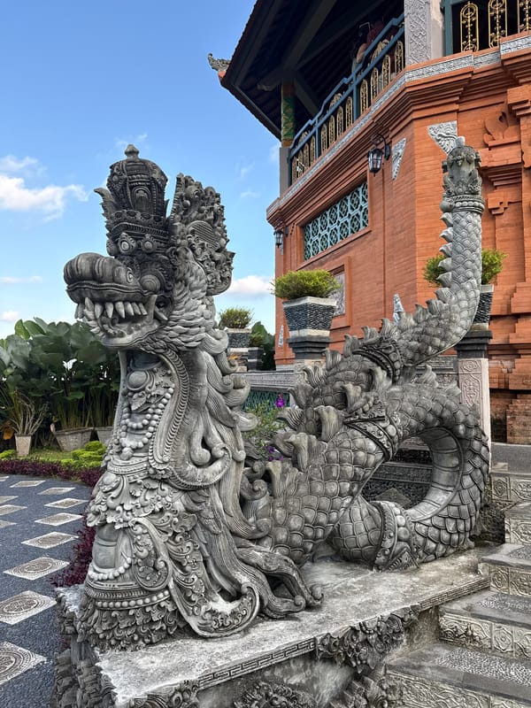 Tourist photographs document Tirtagangga Water Palace stone dragons, Bali