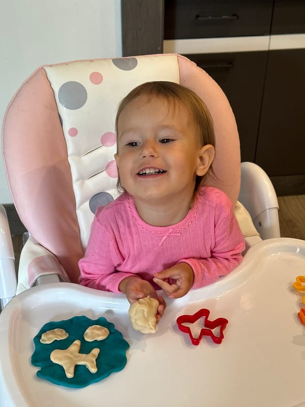 Child plays with playdough in high chair in Wisła