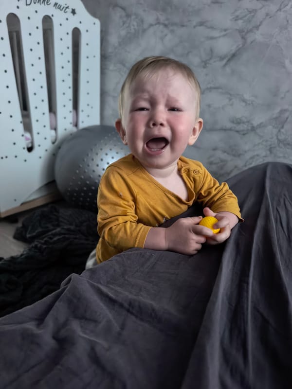 Child crying with yellow ball near crib in Sterlitamak
