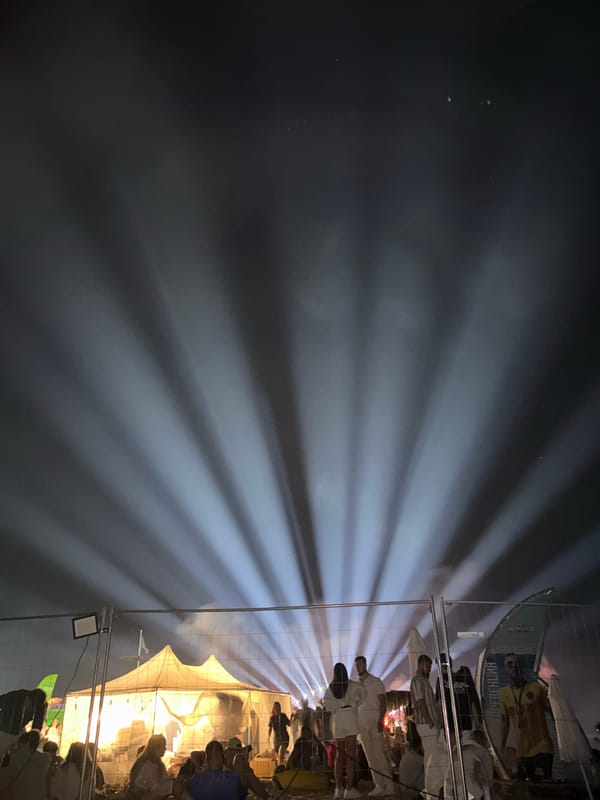 Crowd gathers under glowing tent at nighttime outdoor event