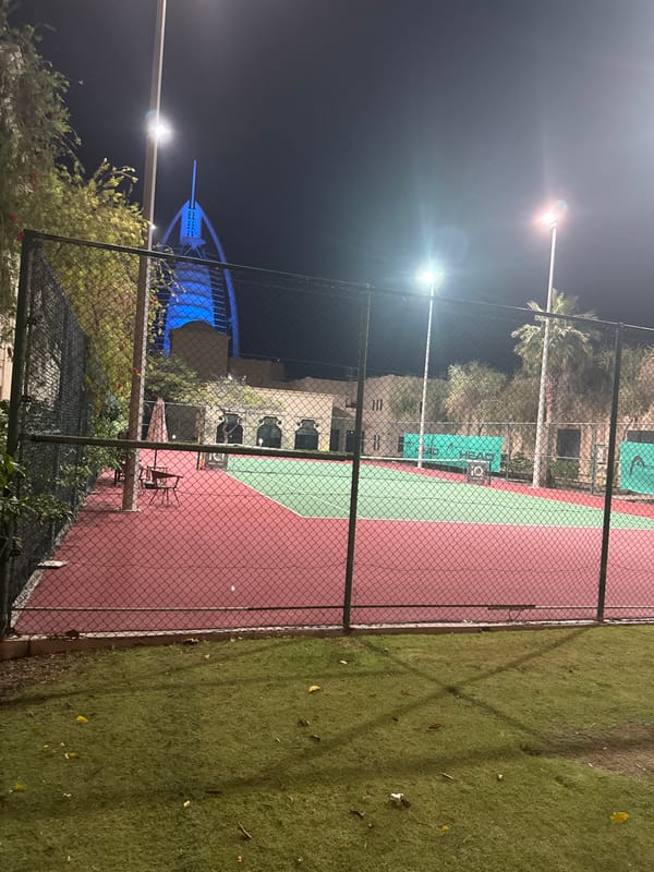 Night tennis court scene with illuminated Burj Al Arab backdrop