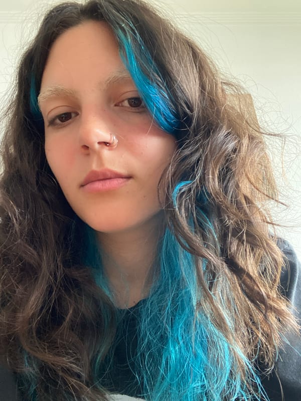 Young person with blue-streaked hair takes selfie in Gijón