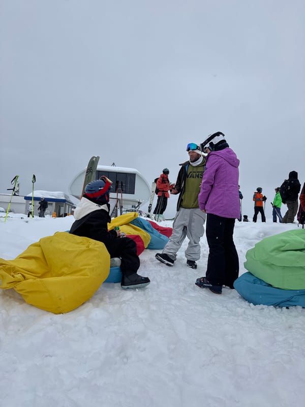 Skier rides gondola lift in black gear and orange goggles