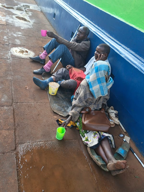 Three people sit against blue wall in Thika, Kenya
