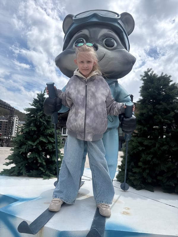 Girl poses with skiing character statue in Estosadok