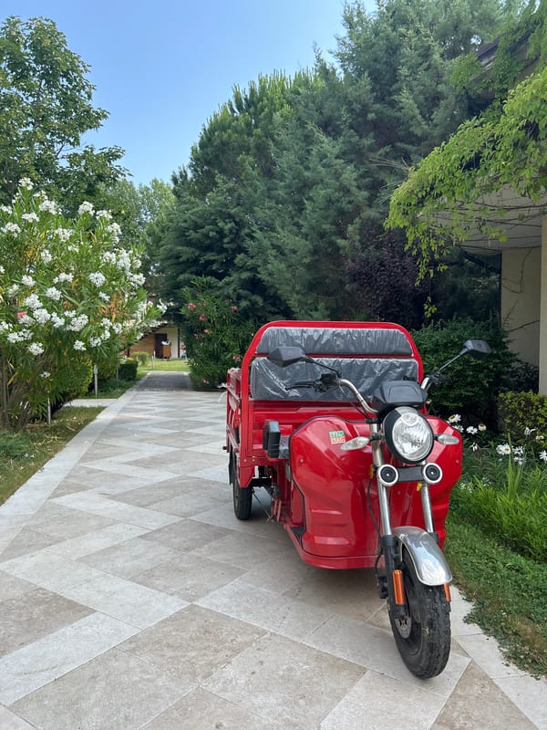 Red three-wheeled motorcycle parked on a patterned tile pathway