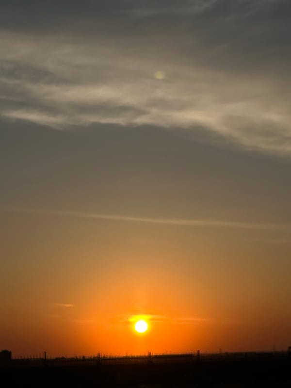 Sunset observed over city with orange-yellow sky coloration