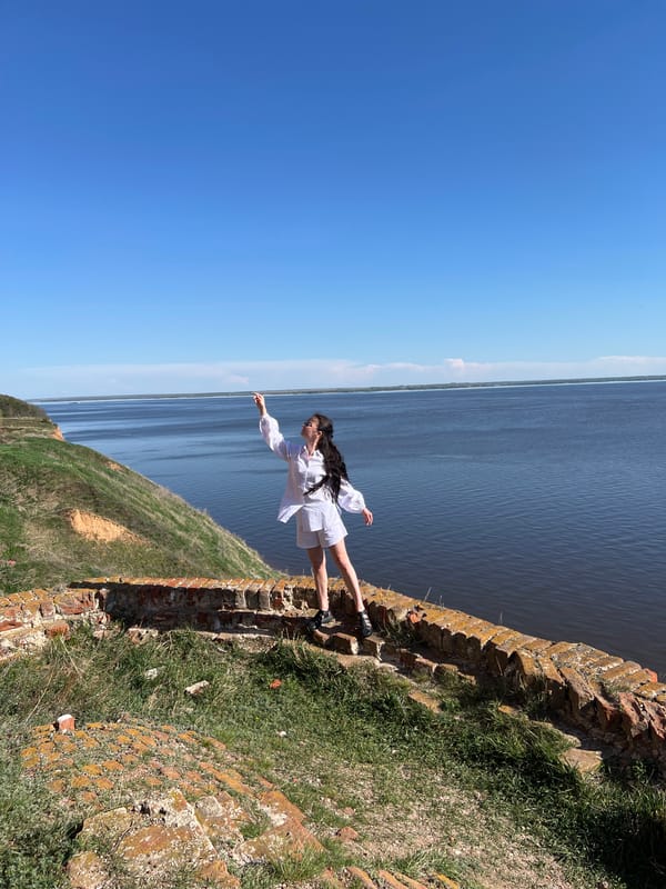 Tourists explore historic church ruins near water in Shuran, Russia