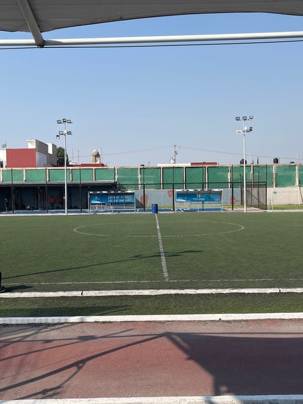 Person adjusts shoes at soccer field during afternoon visit