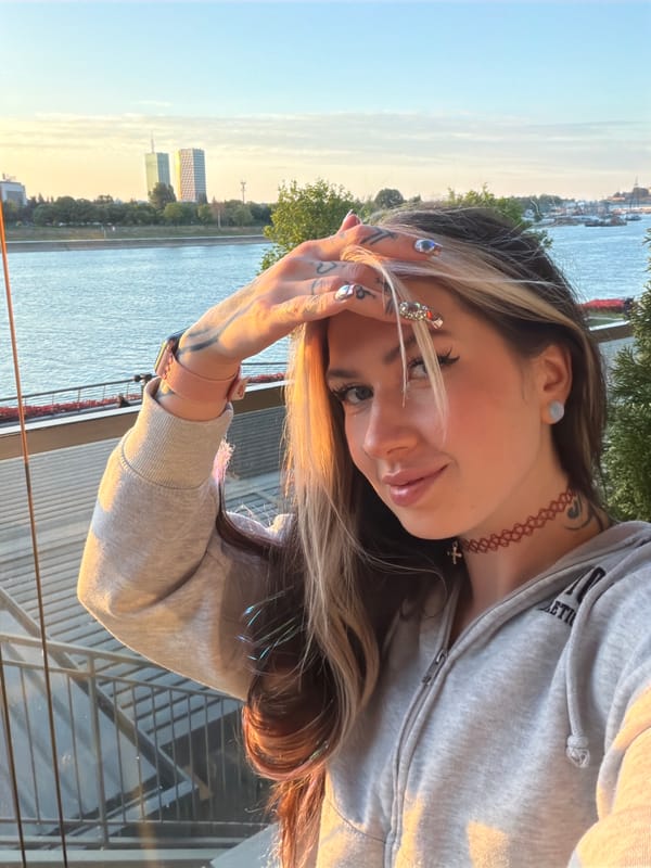 Woman photographs herself at Belgrade riverfront overlook during golden hour