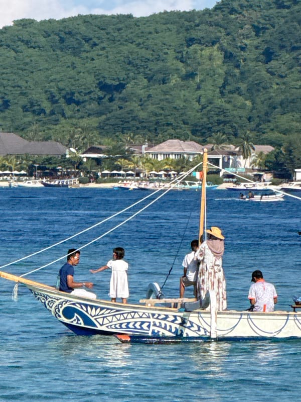 Traditional outrigger canoe navigates Indonesian coastal waters with crew