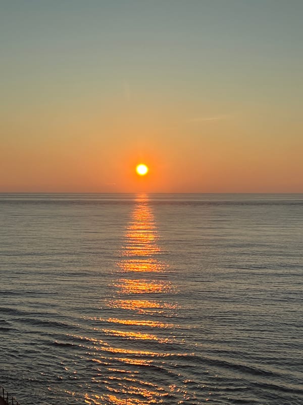 Cargo ship at sea during a calm open-ocean sunset