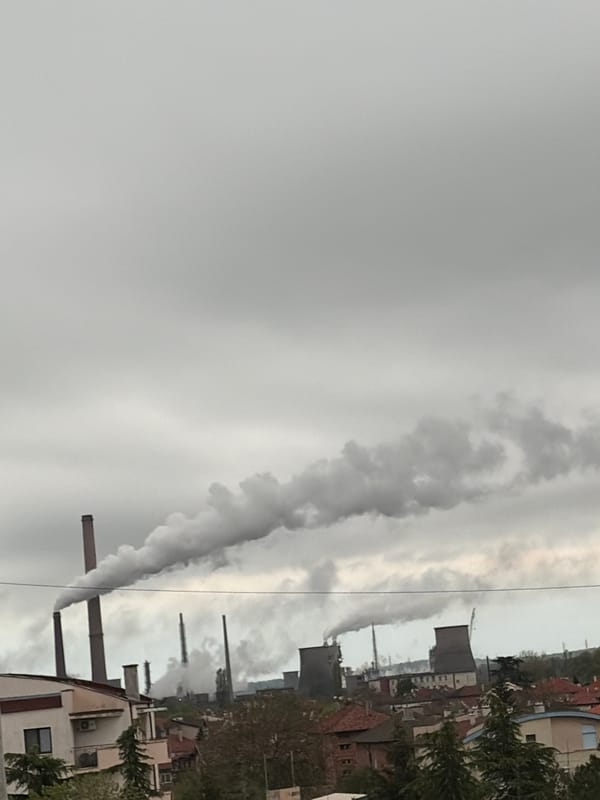 Industrial landscape with smokestacks observed under grey skies