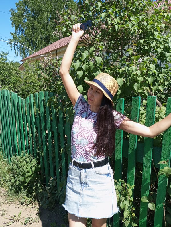 Woman documents sunny day in Russian village with photos, art
