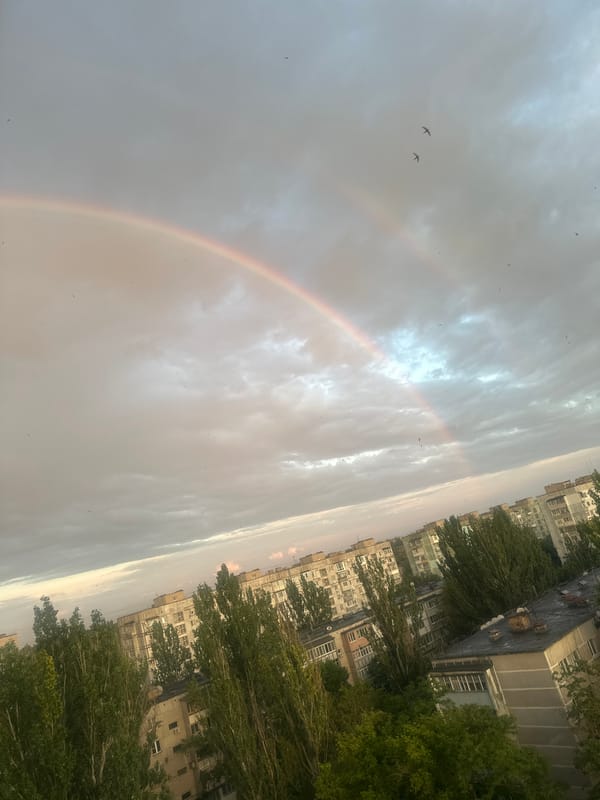 Double rainbow over a cloudy city skyline