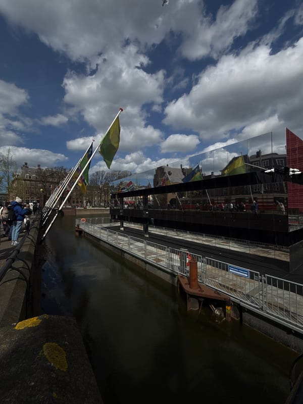 Canal scene documented in The Hague with pedestrians, flags