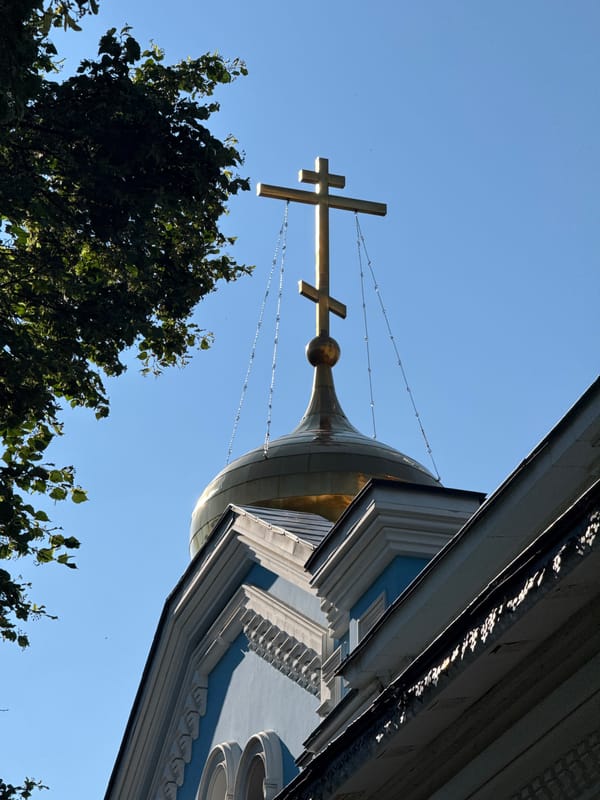 Blue Orthodox church with gold domes and bell tower, sunny day