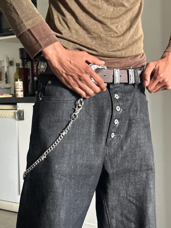 Man adjusts ornate belt on jeans in Paris