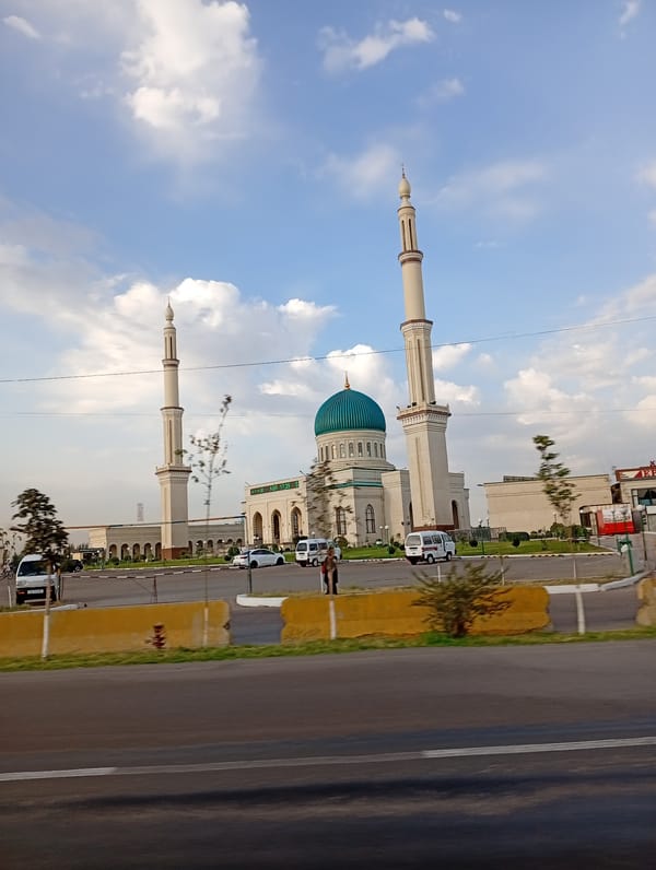 Street-level glimpse of Ohangaron's mosque and city traffic