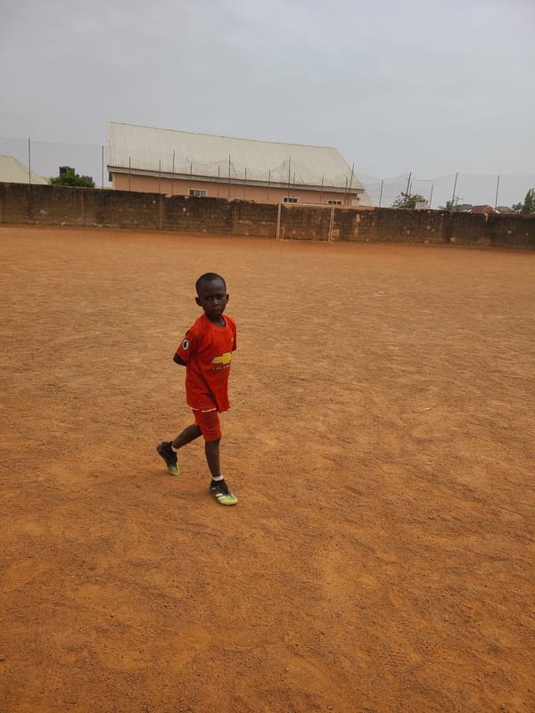 Young boys play soccer on dirt field in Nigeria